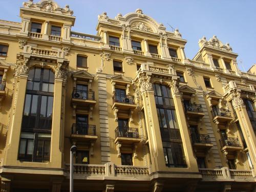 un gran edificio amarillo con ventanas y balcones en Hostal Avenida, en Madrid