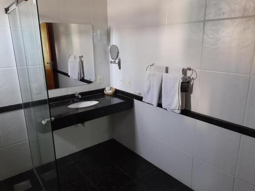 a bathroom with a sink and a mirror and towels at Constantino Hotel e Eventos in Juiz de Fora