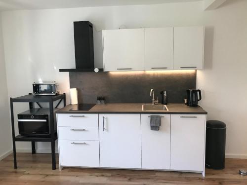 una cocina con armarios blancos y fregadero en Apartment Stockholm, top renoviert, 35qm, Köln nah, en Bergisch Gladbach