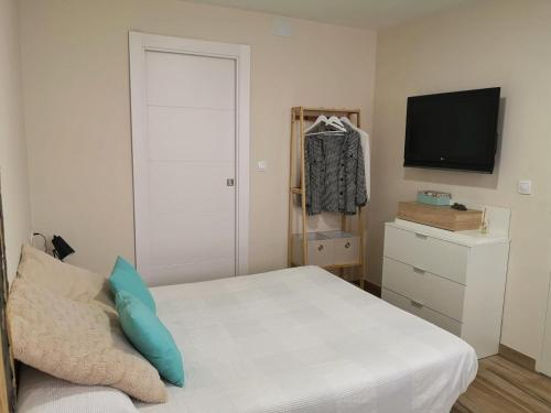 um pequeno quarto com uma cama e uma televisão em Apartamento acogedor en Granada em Granada