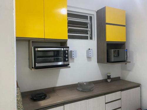 a kitchen with yellow cabinets and a microwave at Studio em Copacabana in Rio de Janeiro