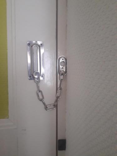 une porte en métal avec une chaîne attachée à celle-ci; dans l'établissement Chambre meublée au cœur de ville - chez l'habitant, au Creusot