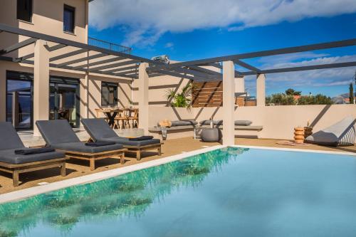 a swimming pool with chairs and a house at Ionian Village in Lixouri