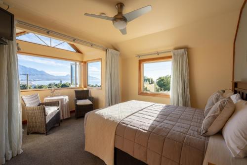 Nikau Lodge في كايكورا: غرفة نوم بسرير وكرسي ونوافذ