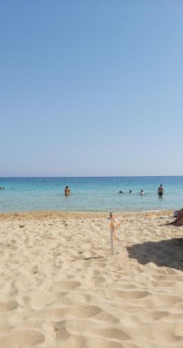 a young boy standing on a beach with people in the water at Panthoma Casa in Ayia Napa