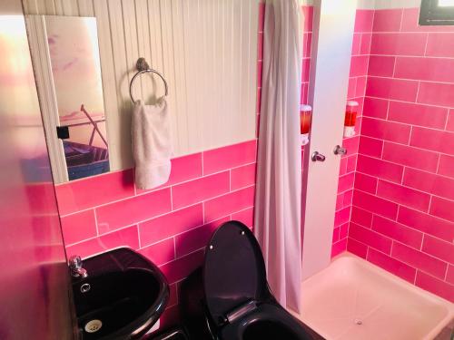 a pink bathroom with a black toilet and a sink at Surfari Punta Rocas in Punta Negra