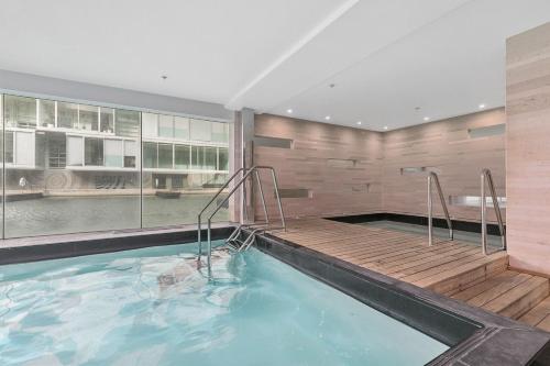 a swimming pool with a wooden deck and a large window at QV Stays Upscale Modern Viaduct Haven in Auckland