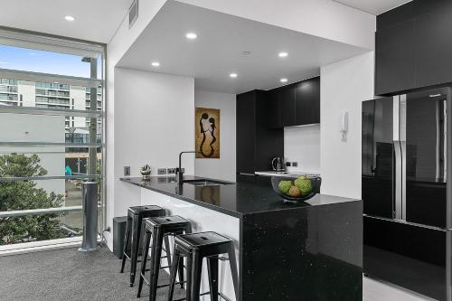 a black and white kitchen with a counter and stools at QV Stays Upscale Modern Viaduct Haven in Auckland
