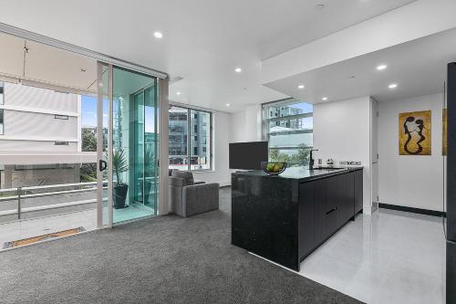 a kitchen with a black island in a living room at QV Stays Upscale Modern Viaduct Haven in Auckland