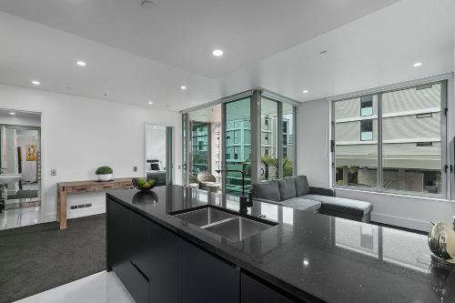 a kitchen with a sink and a living room at QV Stays Upscale Modern Viaduct Haven in Auckland