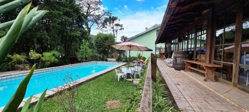 a swimming pool next to a building with an umbrella at Pousadinha Lá em Casa in Petrópolis