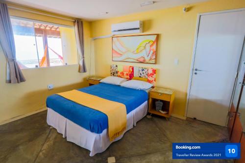 Un dormitorio con una cama azul y amarilla y una ventana en Casa a beira mar com 4 suites e muito conforto, en Porto de Galinhas