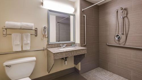a bathroom with a toilet and a sink and a mirror at Best Western Rayne Inn in Rayne