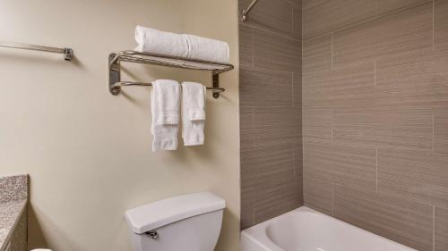 a bathroom with a toilet and a shower with towels at Best Western Rayne Inn in Rayne