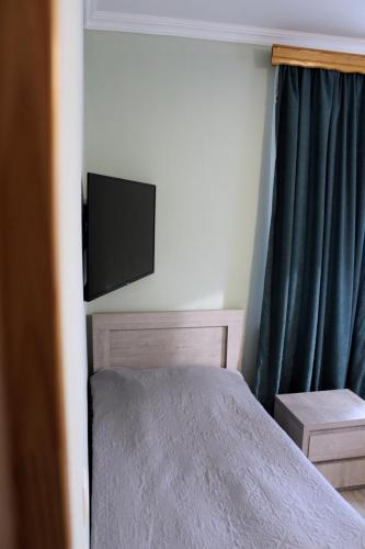 a bedroom with a bed and a flat screen tv at Guest House on Meskheti in Borjomi