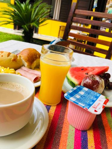 - une table avec une assiette de nourriture et une tasse de jus d'orange dans l'établissement Pousada Casa Do Mar, à Parati