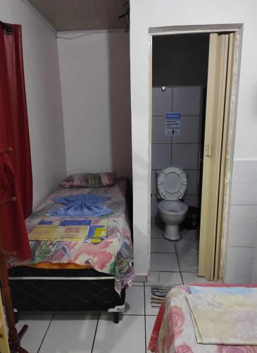 a small bedroom with a bed and a toilet at Pousada Piratas Di San Rocco in Maceió