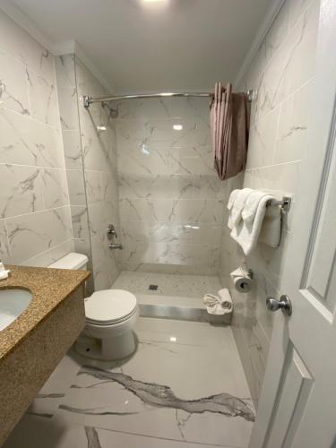 a white bathroom with a toilet and a sink at Relax Inn North Babylon in North Babylon