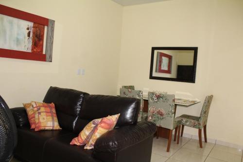 a living room with a black leather couch and a table at Edicula Brotas in Brotas
