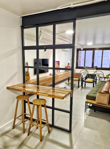 a table and two stools in a living room at Apartamento Artístico - Garagem - Ar Condicionado - Excelente Localização in Bento Gonçalves