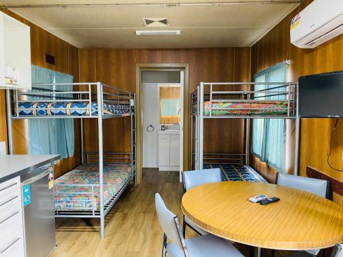 a room with two bunk beds and a table and chairs at Mt Mittamatite Caravan Park in Corryong
