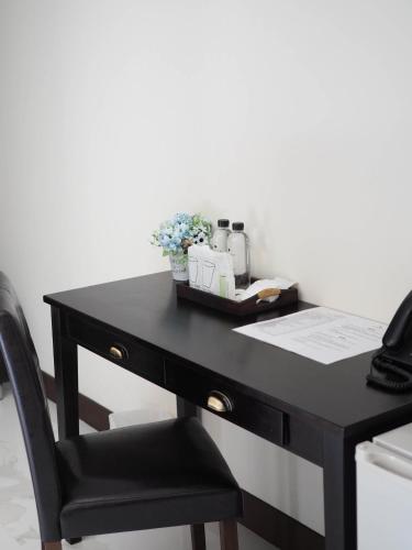 a black desk with a chair next to a white wall at Khampare Chiang Mai Hotel in Chiang Mai