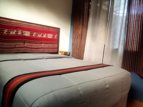 a bedroom with a bed with a red headboard at Casa Mirador guesthouse in Cusco