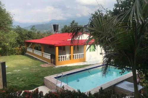 uma casa com um telhado vermelho e uma piscina em CASA DE CAMPO Villa Ibiza - EXCELENTE DESCANSO em Betulia