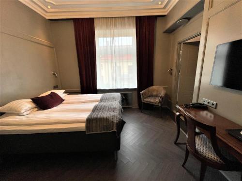 a hotel room with a bed and a desk and a television at Hotel Vasa, BW Signature Collection in Gothenburg