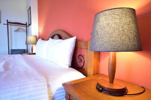 a lamp on a wooden table next to a bed at Ji Li Ya Lan Homestay in Chenggong