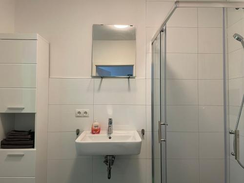 a white bathroom with a sink and a shower at Stilvoll Wohnen in Oldenburg Kreyenbrück Apartments in Oldenburg