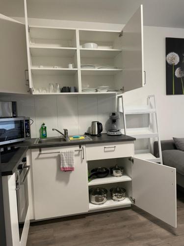 a small kitchen with white cabinets and a sink at Stilvoll Wohnen in Oldenburg Kreyenbrück Apartments in Oldenburg
