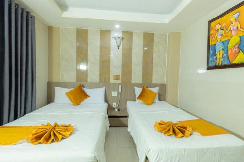 two beds in a hotel room with orange bows on them at Oliver Hotel in Nha Trang