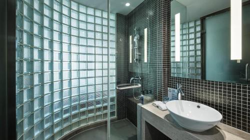 Holiday Inn Express Shanghai Gongkang, an IHG Hotel في Baoshan: حمام مع حوض ودش زجاجي