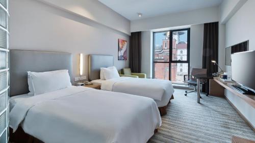 Cette chambre comprend deux lits et une télévision. dans l'établissement Holiday Inn Express Shanghai Gongkang, an IHG Hotel, à Baoshan