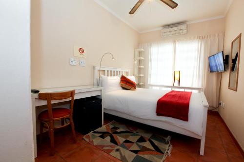 a bedroom with a bed and a desk and a chair at Roof of Africa Hotel in Windhoek