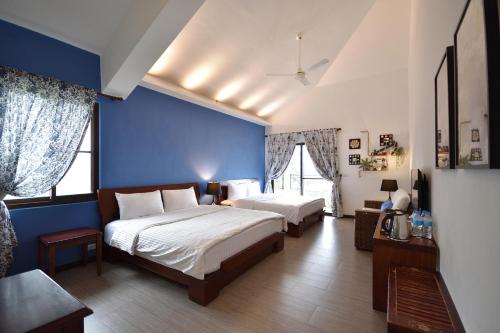 a bedroom with two beds and a blue wall at Ji Li Ya Lan Homestay in Chenggong