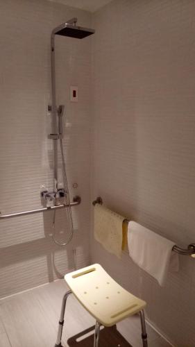 a shower with a white chair in a bathroom at Greet Inn in Kaohsiung