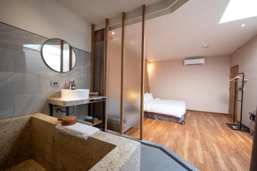 a bathroom with a tub and a sink and a bed at Yunoyado Onsen Hot Spring Hotel Deyang in Jiaoxi