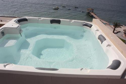 a large hot tub on top of a building next to the ocean at Paracas Penthouse first line Boardwalk in Paracas