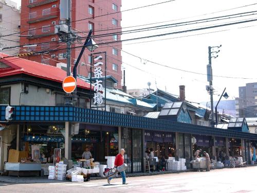 a man crossing a street in front of a store at Granbell hotel Tanuki, Sapporo in Sapporo