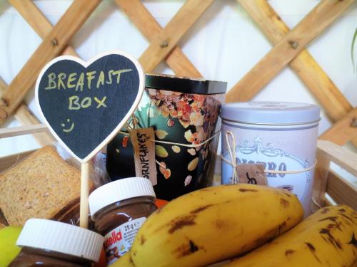 a basket of food with a heart box and bananas at 2 CUORI E 1 YURTA Glamping in Tuscany - Adults Only in Asciano