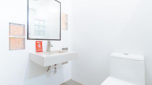 a white bathroom with a sink and a mirror at RedDoorz @ EL Runway Hotel Bulacan in Bulacan