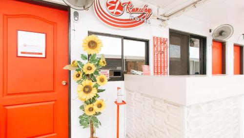 a restaurant with a red door and sunflower wreath at RedDoorz @ EL Runway Hotel Bulacan in Bulacan