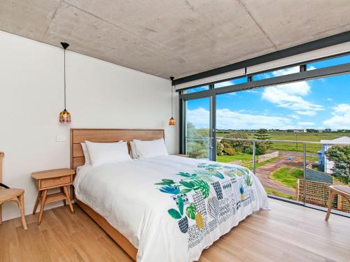 a bedroom with a bed and a large window at Oceanview in Port Fairy