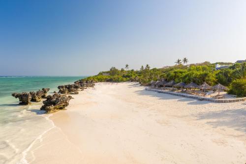 uma praia com uma fileira de cabanas e o oceano em Sunshine Bay Hotel Zanzibar em Matemwe