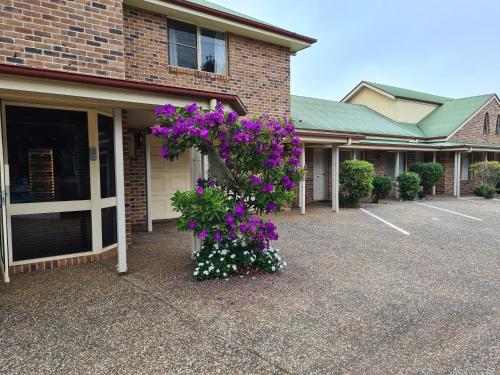 a building with purple flowers in a parking lot at Country Gardens Motor Inn in Toowoomba