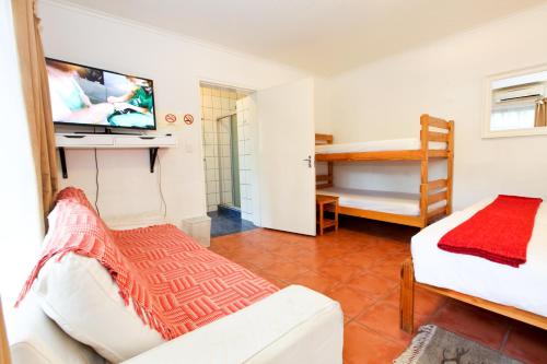 a room with a bed and a tv and a couch at Roof of Africa Hotel in Windhoek