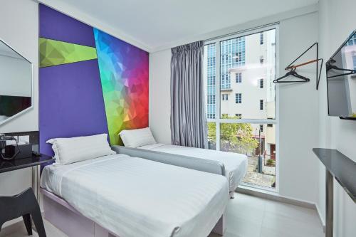 2 letti in una camera con parete arcobaleno di ibis budget Singapore Ametrine a Singapore