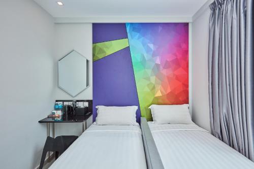 two beds in a room with a colorful wall at ibis budget Singapore Ametrine in Singapore